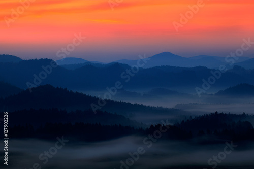 Cold misty foggy morning with twilight sunrise in a fall valley of Bohemian Switzerland park. Hills with fog, landscape of Czech Republic, National park Ceske Svycarsko. Beautiful foggy landscape. © ondrejprosicky