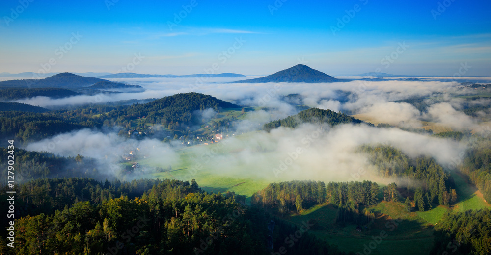 Czech typical summer landscape with fog. Hills and villages with foggy morning. Morning fall valley of Bohemian Switzerland park. Hills with fog, landscape of Czech, Jetrichovice, Ceske Svycarsko.