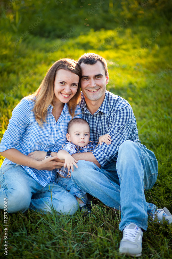 The family father, mother and son smiling and spend time together on the bright green grass. The family father, mother and son smiling and spend time together on the bright green grass.