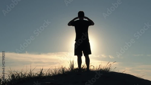 Model released person standing on sand dune overlooks the sunny blue sky at the Oregon Coast on beautiful day then walks away, out of frame.