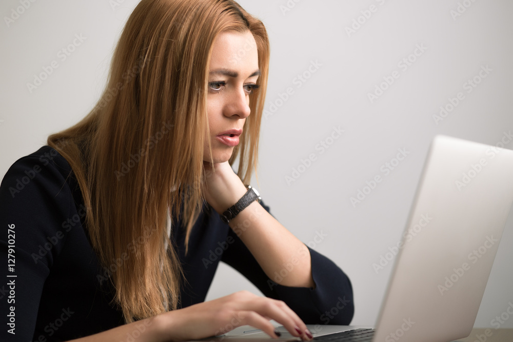 Businesswoman sitting at her workstation in office and working by notebook Businesswoman sitting at her workstation in office and working by notebook