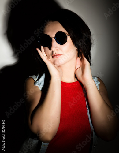 Beautiful young woman with black round sunglasses. Touching glasses.