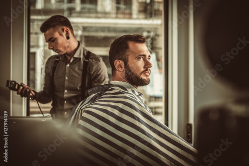 Confident man visiting hairstylist in barber shop. © Nejron Photo