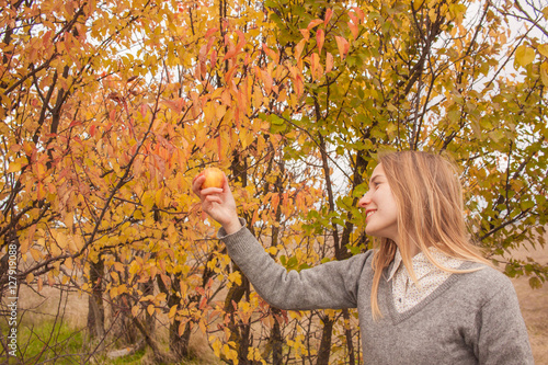 woman watching on apple in the autumn garden 
