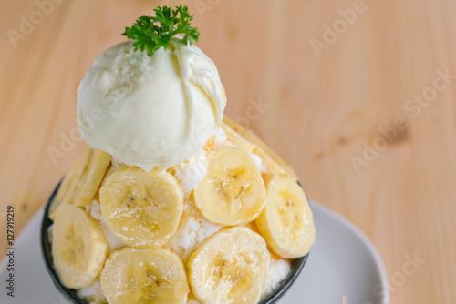 Korean style bing su fresh banana shaved ice on wood table .