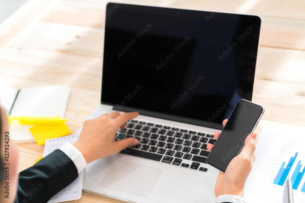 Closeup of business woman hand touch phone over laptop keyboard Closeup of business woman hand touch phone over laptop keyboard