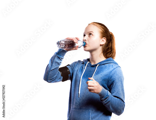 Teenage girl drinking from water bottle. Studio shot, isolated.