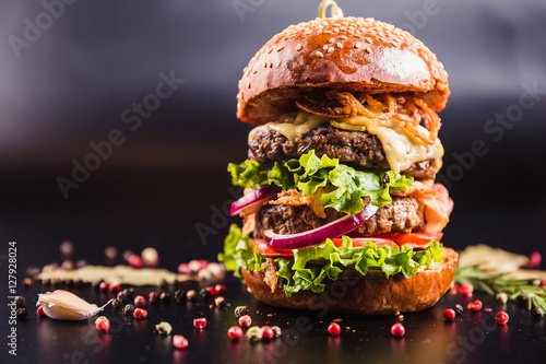 Juicy delicious burger with spices on a black background photo