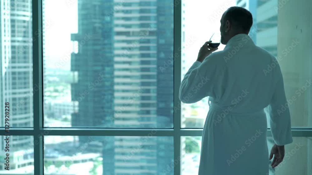 Young man in bathrobe drinking wine and admire view form window at home
Young man in bathrobe drinking wine and admire view form window at home