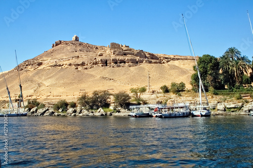 Sightseeing boats and feluccas anchor at the bank of the Nile River. In the background there is the Mausoleum of Aga Khan. photo