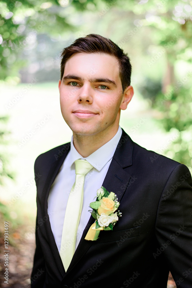 young handsome groom in a black suit standing alone outdoors young handsome groom in a black suit standing alone outdoors