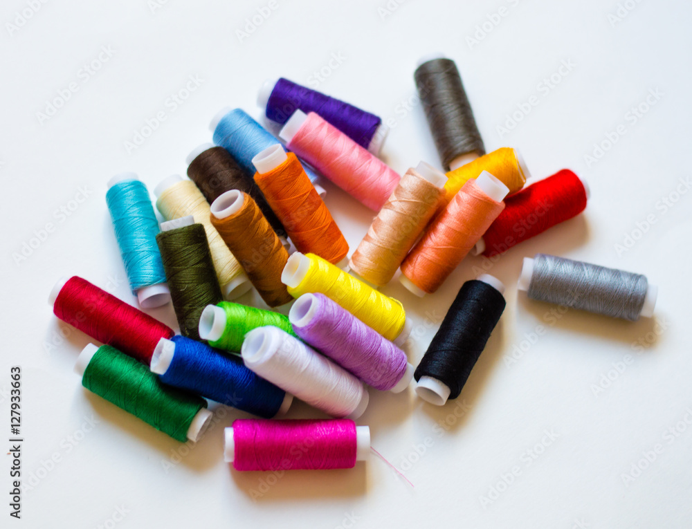 multicolored spools of thread on white background multicolored spools of thread on white background