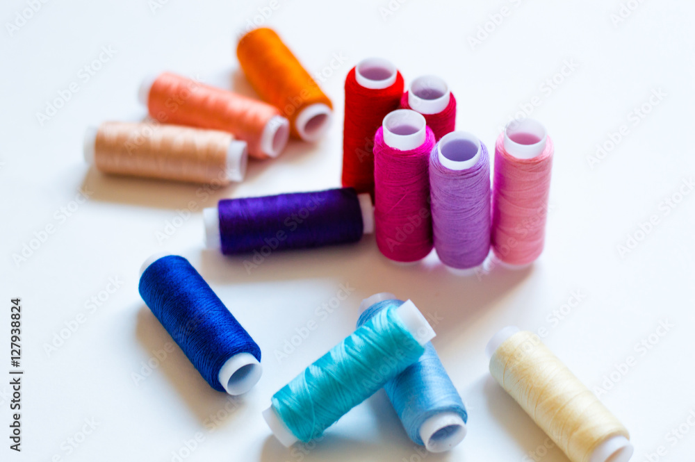 multicolored spools of thread on white background multicolored spools of thread on white background