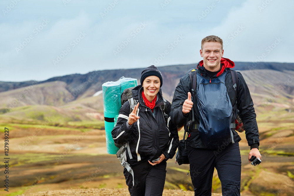 couple joyfull hikers on the trail in the Islandic mountains. Trek in National Park Landmannalaugar, Iceland
