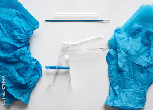 Disposable set for gynecological examination. From left to right are shoe covers, speculum, cervix brush, transport tube to deliver endocervical scraping to laboratory, gloves and draw sheet. photo
