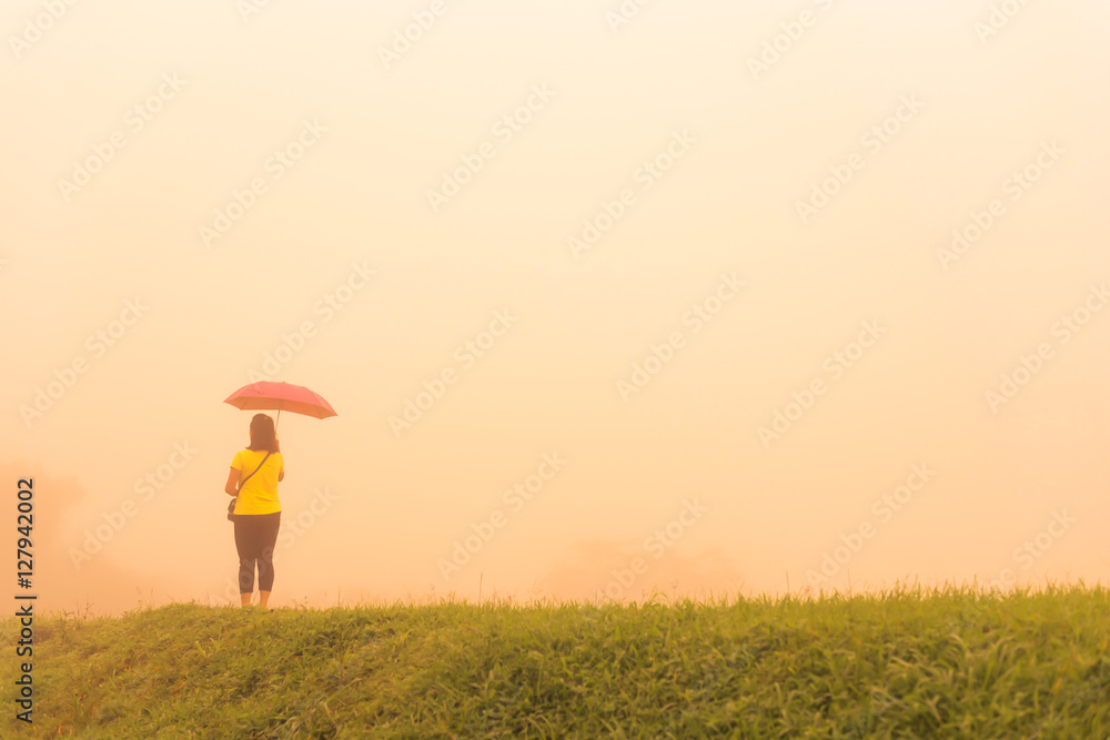 Woman alone in fog with pink umbrella