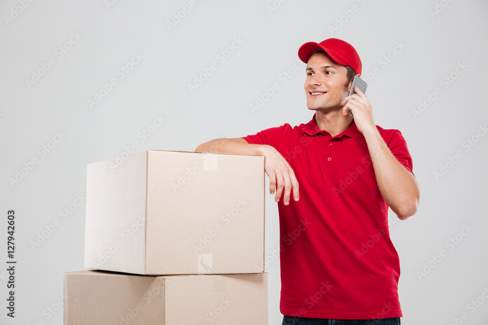 Delivery man talking on mobile phone at stack of boxes Delivery man talking on mobile phone at stack of boxes