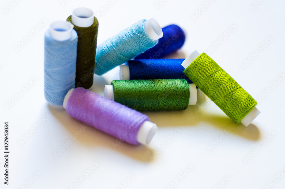 multicolored spools of thread on white background multicolored spools of thread on white background