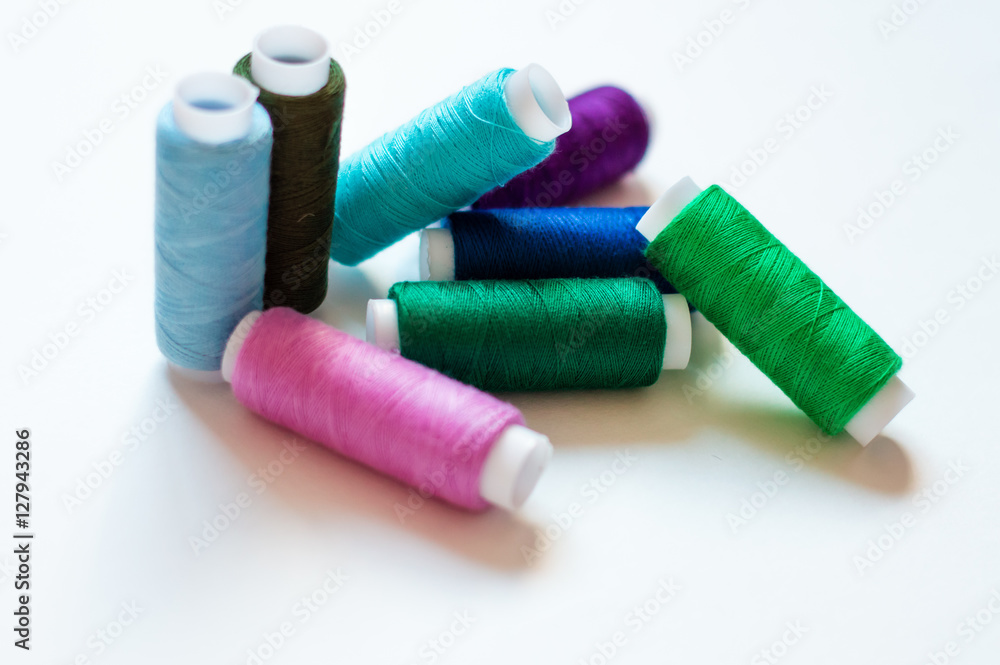 multicolored spools of thread on white background multicolored spools of thread on white background