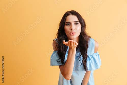 Cute woman in blue dress blowing kiss at camera
