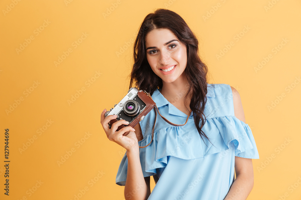Fototapeta premium Portrait of a smiling young brunette girl holding photo camera