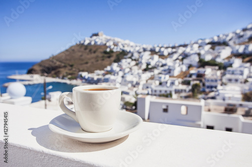 Fototapeta Naklejka Na Ścianę i Meble -  Traditional greek coffee on a balcony with beautiful greek mediterranean town on the background. Vacations in Greece