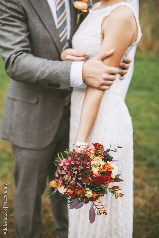 Stylish autumn newlyweds holding a bright marsala wedding bouquet Stylish autumn newlyweds holding a bright marsala wedding bouquet