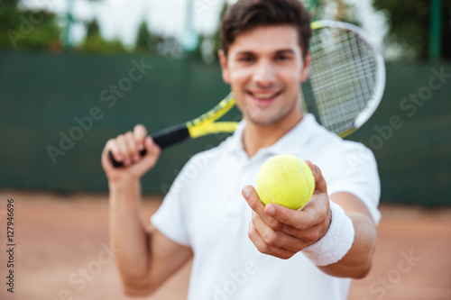 Young tennis man giving ball