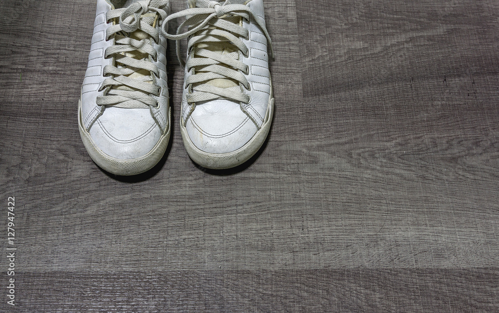 Old white shoes on the wood floor with high contrast