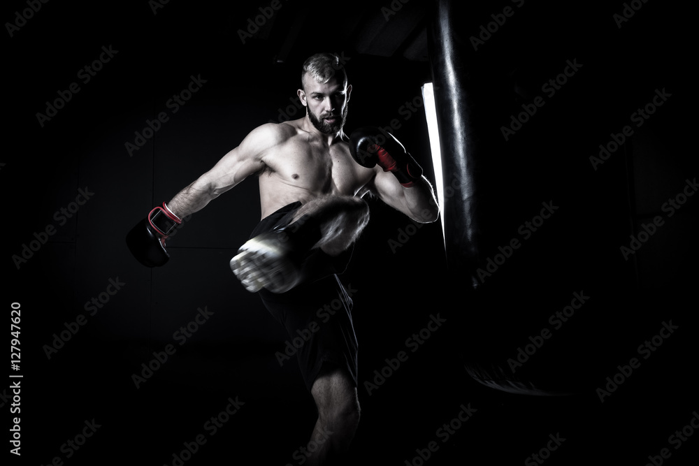 Male Athlete boxer punching a punching bag with dramatic edgy li