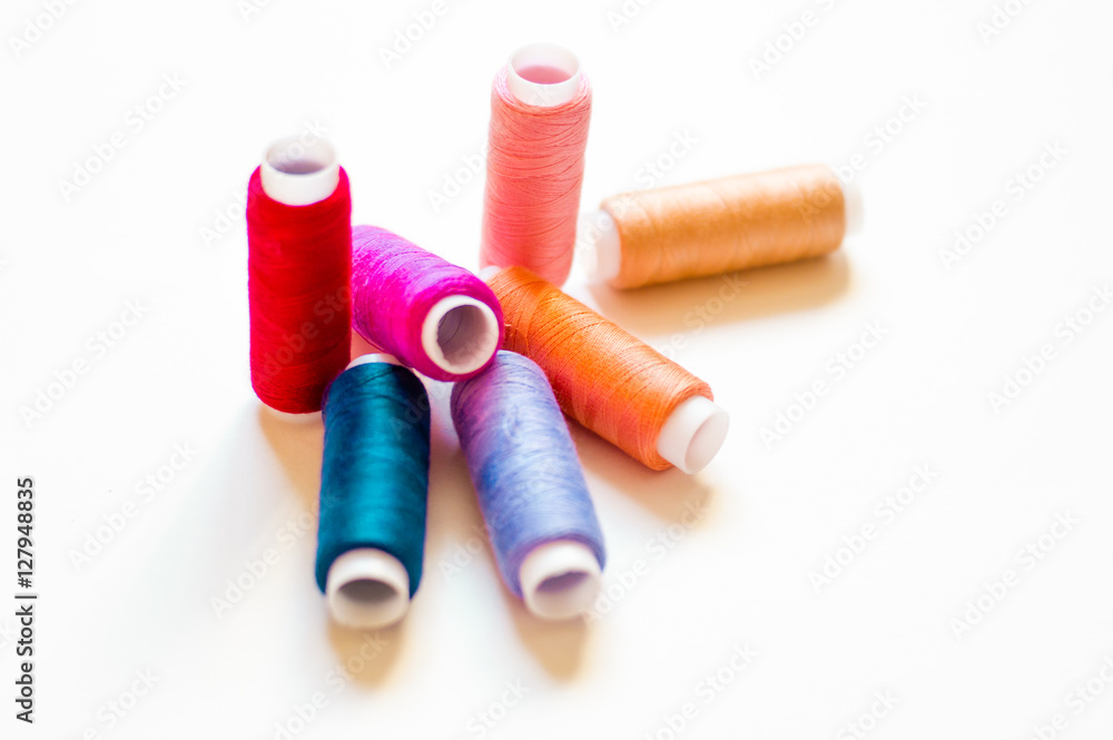 multicolored spools of thread on white background multicolored spools of thread on white background