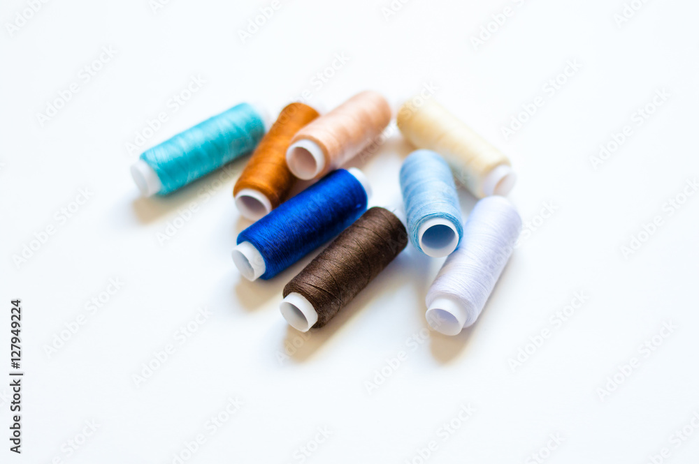 multicolored spools of thread on white background multicolored spools of thread on white background