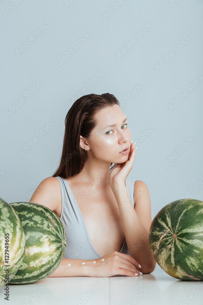 Pretty young woman sitting at the table with fresh watermelons Pretty young woman sitting at the table with fresh watermelons