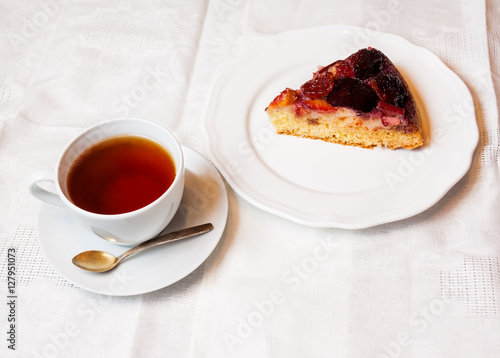 Plum cake and cup of tea on table