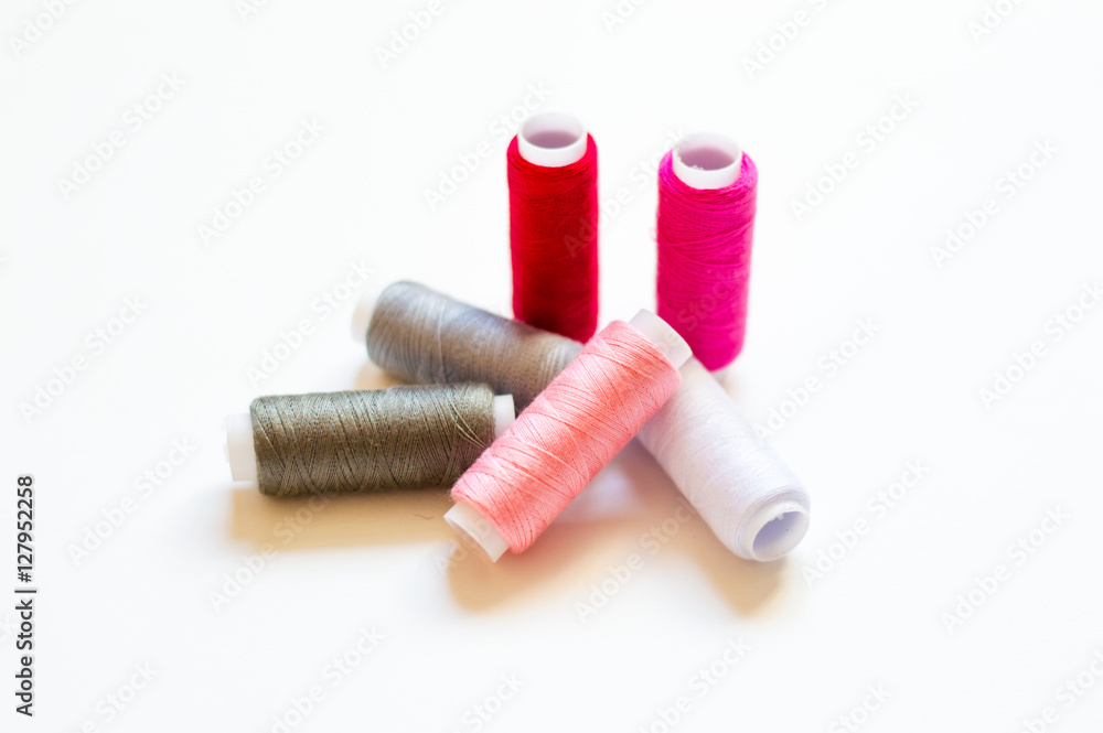 multicolored spools of thread on white background multicolored spools of thread on white background