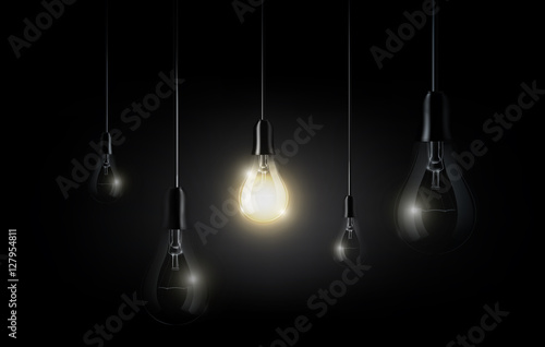 Glowing light bulb is hanging between a lot of turned off light bulbs on dark black background, copyspace, transparent vector