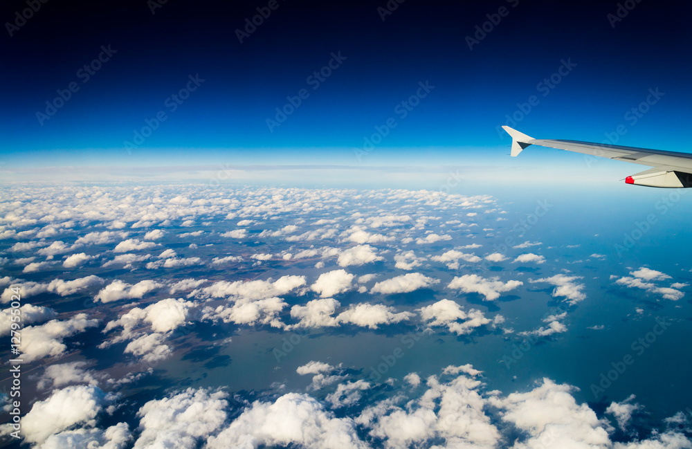 Fototapeta premium clouds in rows from aircraft with deep blue sky with land and sea below