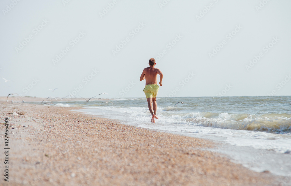 Man jogging on the desert sea line at the morning time