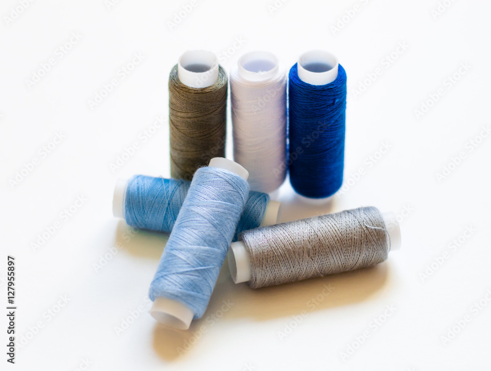 multicolored spools of thread on white background