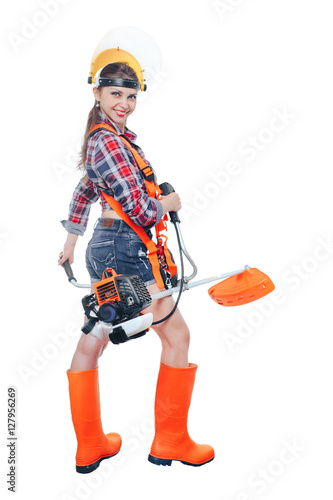 Girl in helmet holding in his hand a petrol trimmer