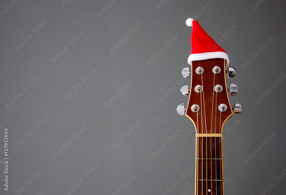 Obraz premium Red Christmas hat on guitar with grey background, Merry Christmas song