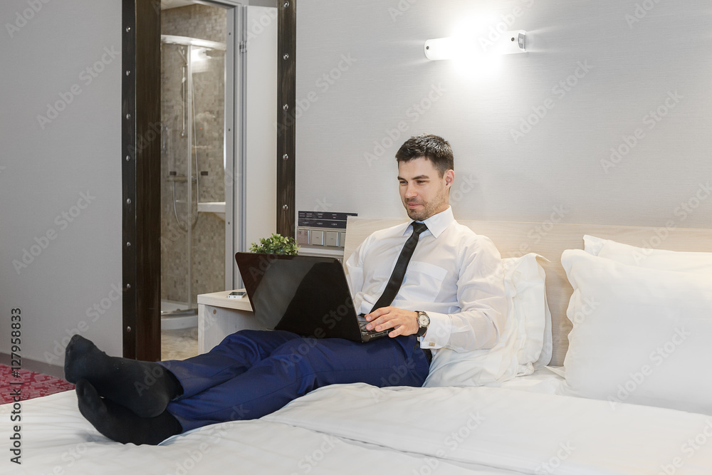 Young businessman working in his hotel room with his laptop
