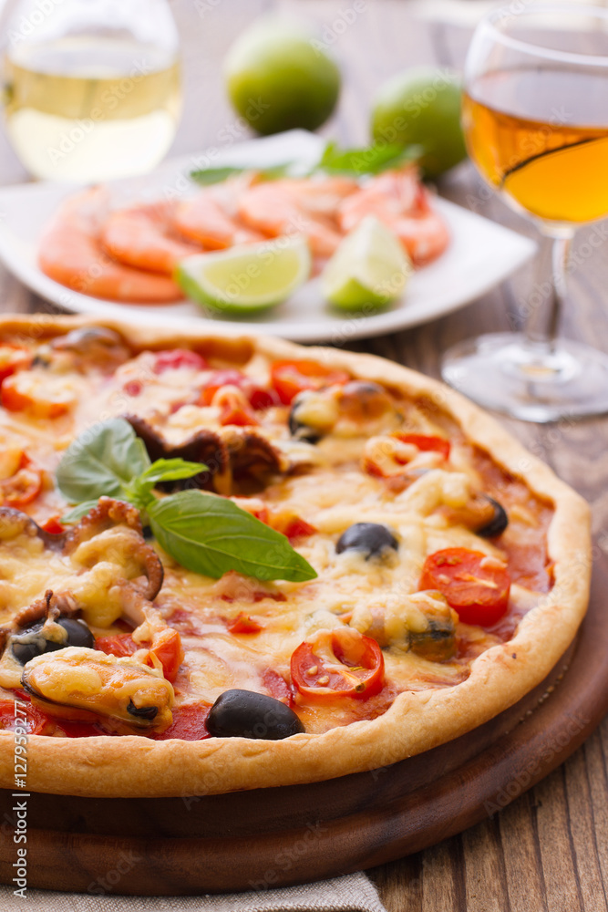 Big tasty pizza with seafood, tomatoes, wine on wooden table Big tasty pizza with seafood, tomatoes, wine on wooden table