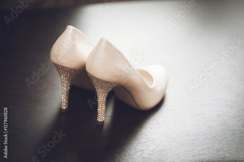 White bridal wedding shoes on wooden table. Marriage concept