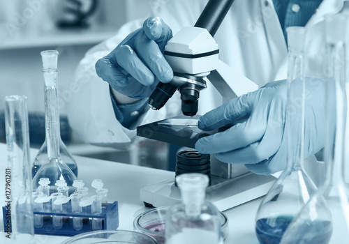 woman in a laboratory microscope with microscope slide in hand.toned image.