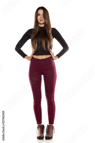 young model in burgundy pants and a black blouse on a white background