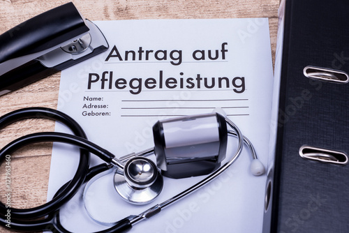 Antrag auf Pflegeleistung auf Holztisch mit Ordner und Stethosko