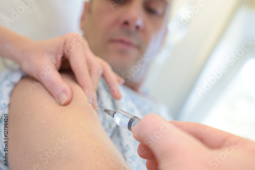 doctor puts syringe in male arm