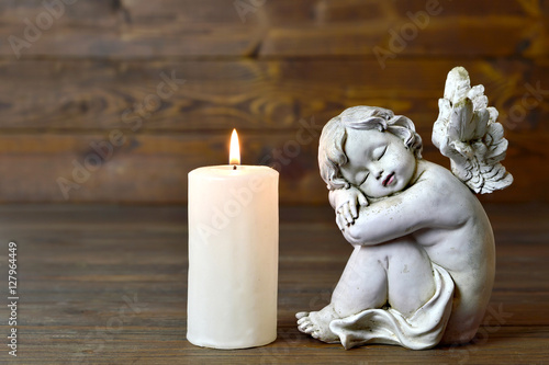 Angel and candle on wooden background