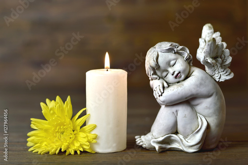 Angel, candle and flower on wooden background
